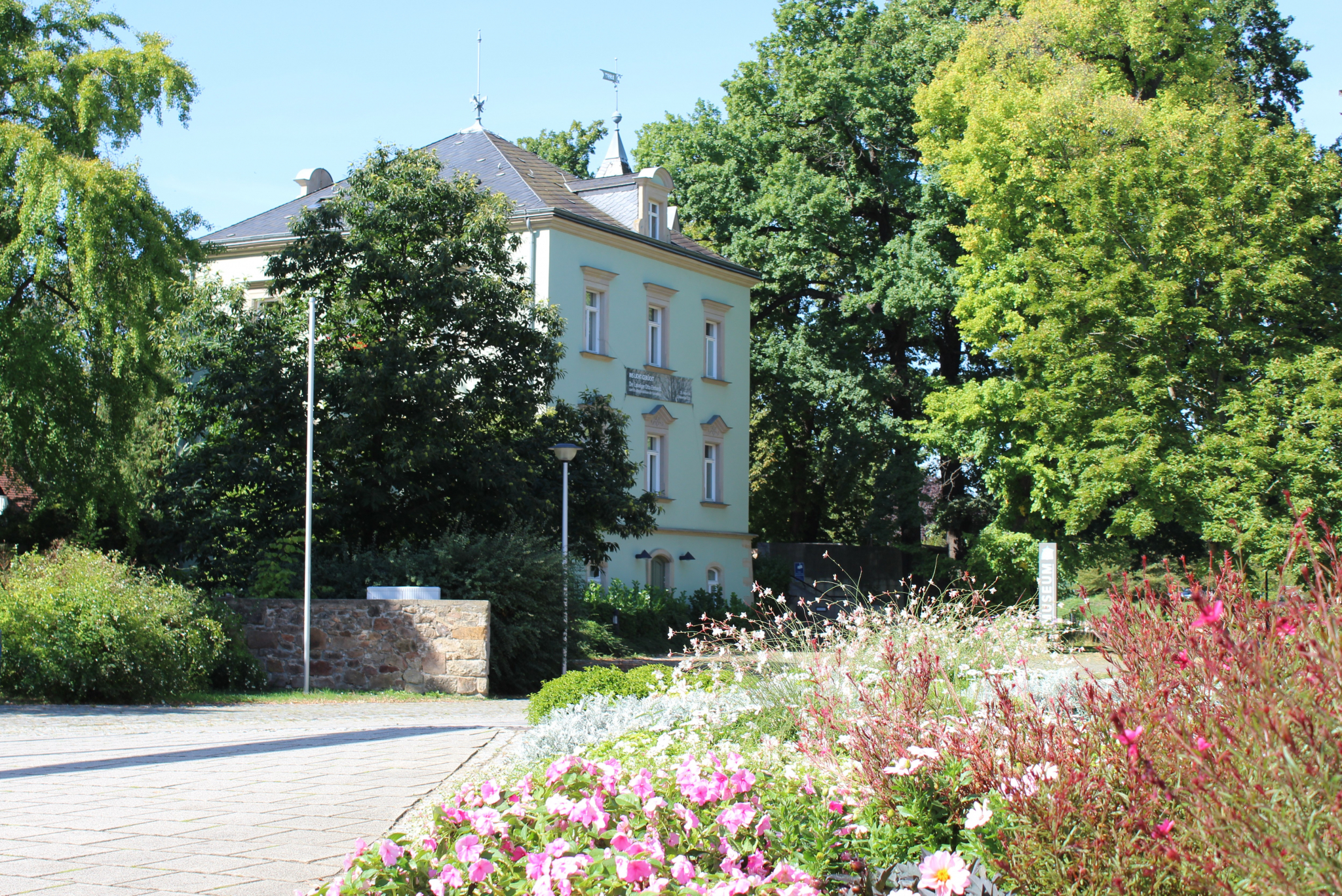 Außenansicht Karrasburg mit Banner, mit Blumen im Vordergrund